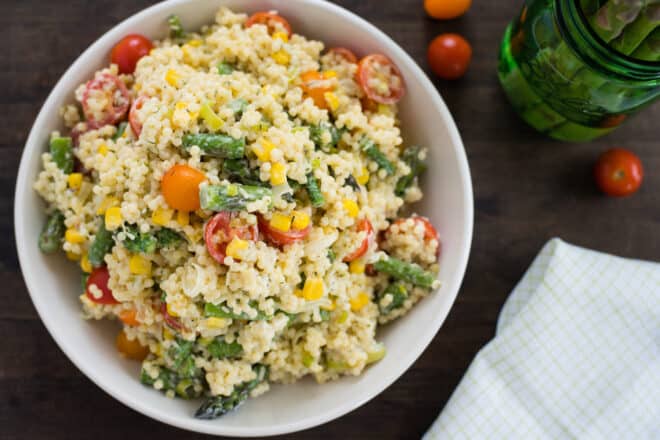 White bowl filled with acini di pepe pasta salad with tomatoes, asparagus and corn.