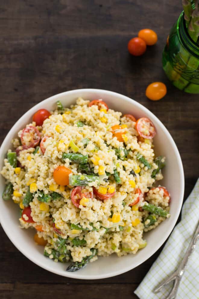 Shallow white bowl filled with pasta saiad made with small shape pasta and vegetables.