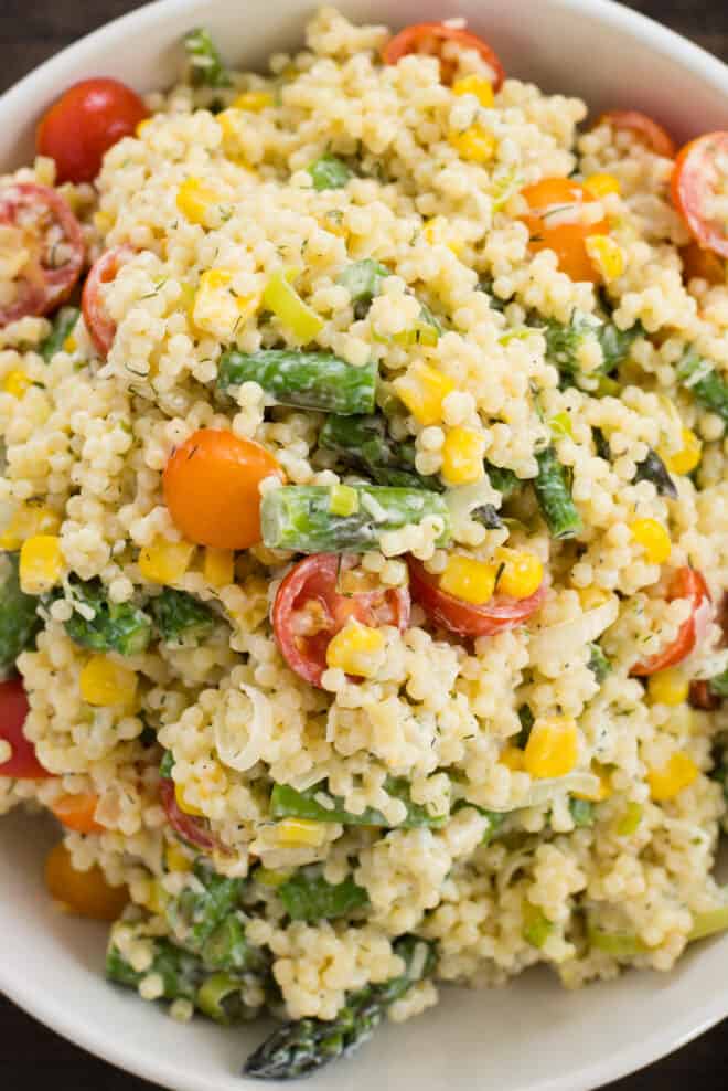 Close up photo of small balls of pasta with vegetables and creamy dressing.