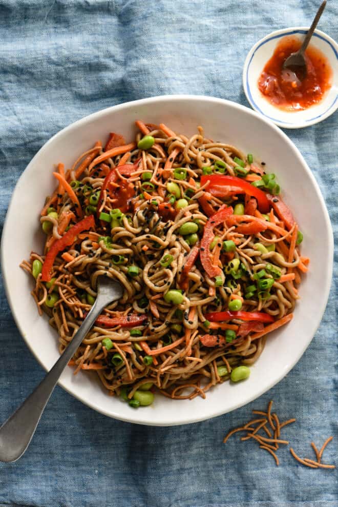 Large white bowl filled with Asian noodle salad, with fork twirling some noodles.