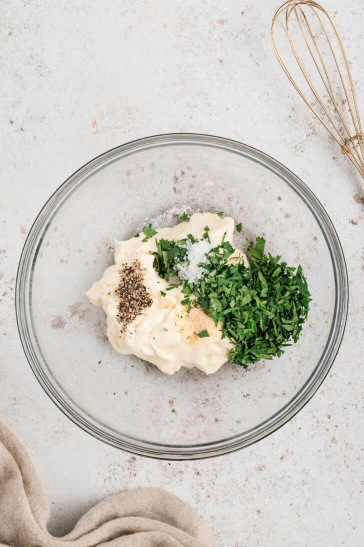 Mayonnaise, chopped cilantro, garlic powder and salt and pepper in a glass bowl.