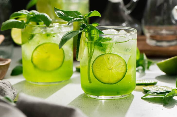 Basil vodka cocktails on a shadowy countertop.