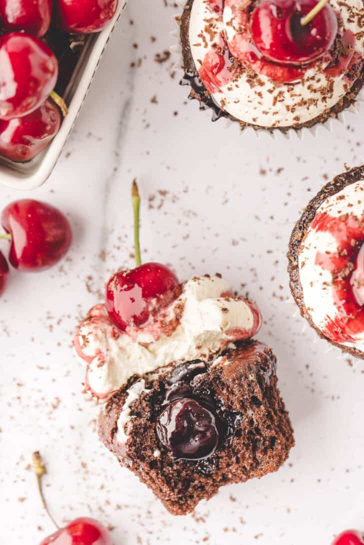 An image showing the inside of a cherry filled cupcake as it rests on a light surface.