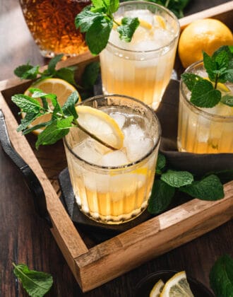 A tray filled with bourbon smash drinks garnished with mint sprigs.