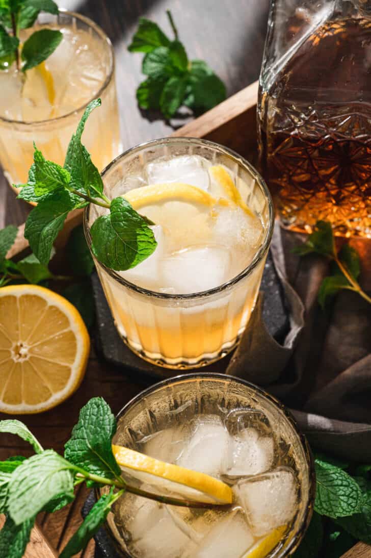 A tray filled with bourbon smash drinks garnished with mint sprigs.