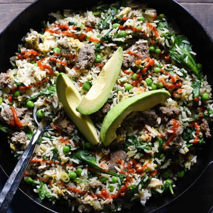 Cast iron skilled filled with breakfast fried rice, topped with avocado slices.