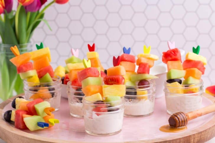 Fruit salad for easter, served on skewers in small mason jars with cottage cheese dip in the bottom of each jar.