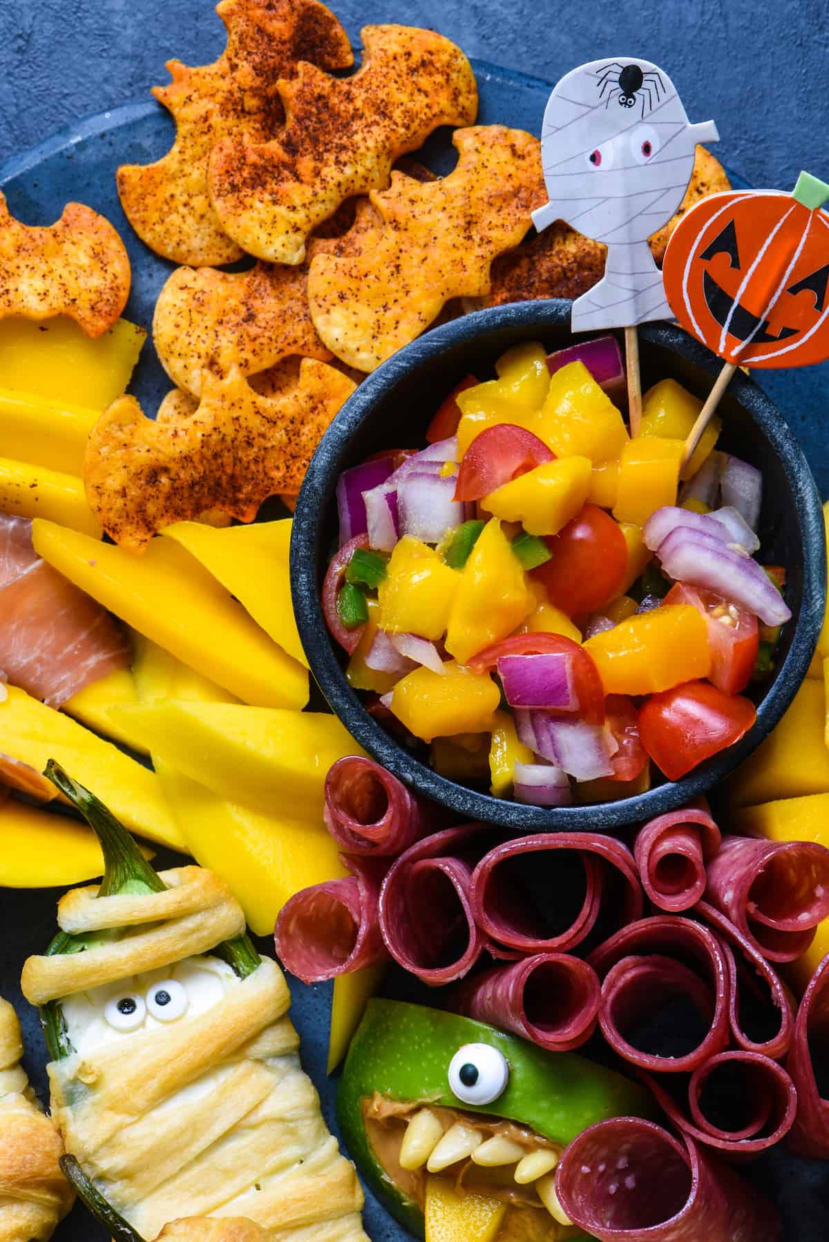 Closeup of small bowl of chopped mango salsa with tortilla chip "bats"