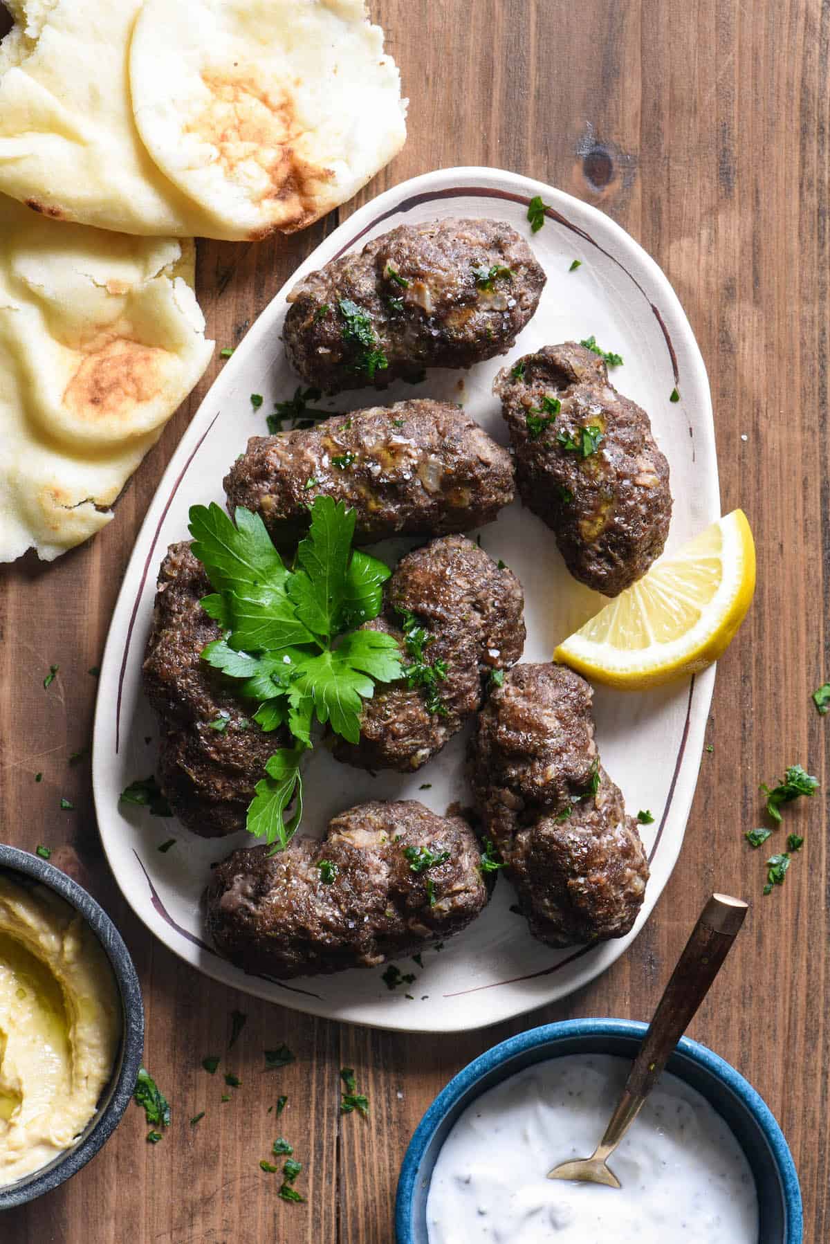 Lebanese beef kafta on small platter garnished with lemon wedge and fresh parsley.