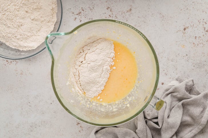 The beginnings of a cookie dough with an flour in the glass bowl of a stand mixer.