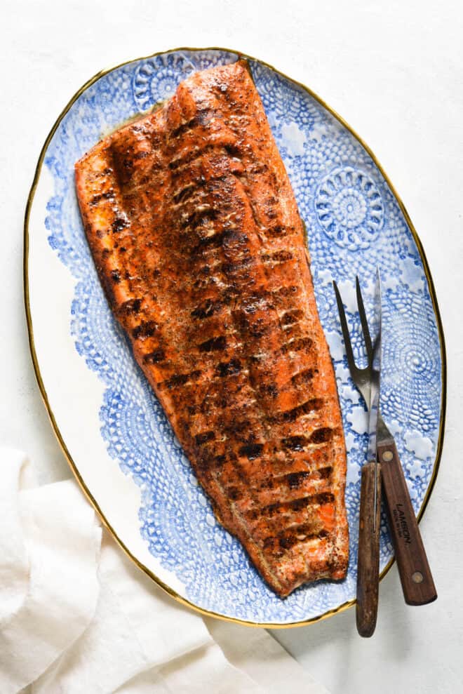 Decorative blue and white platter topped with large piece of grilled sockeye salmon.