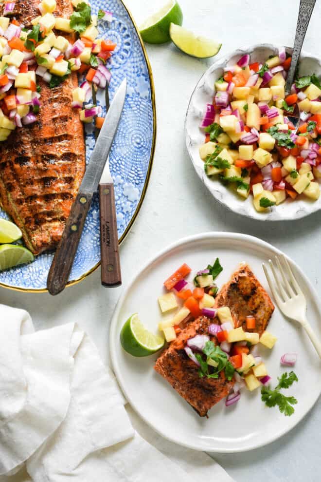 Meal scene featuring a platter and a smaller plate of salmon with pineapple salsa being served.