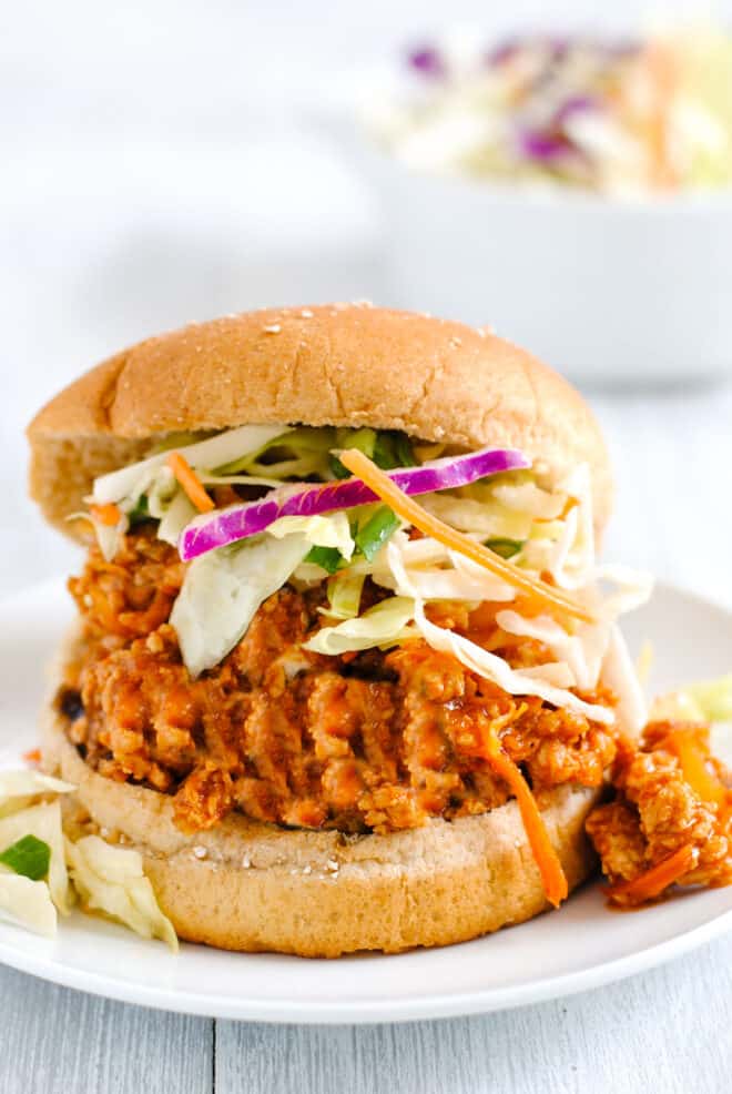 Wheat hamburger bun filled with Asian sloppy joe mixture and shredded vegetables.