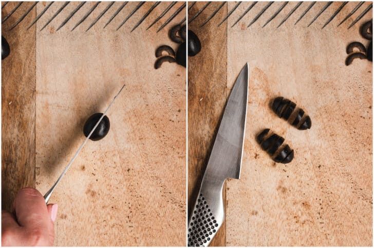 A wooden cutting board and stainless steel knife demonstrating how to cut a black olive to look like a spider.