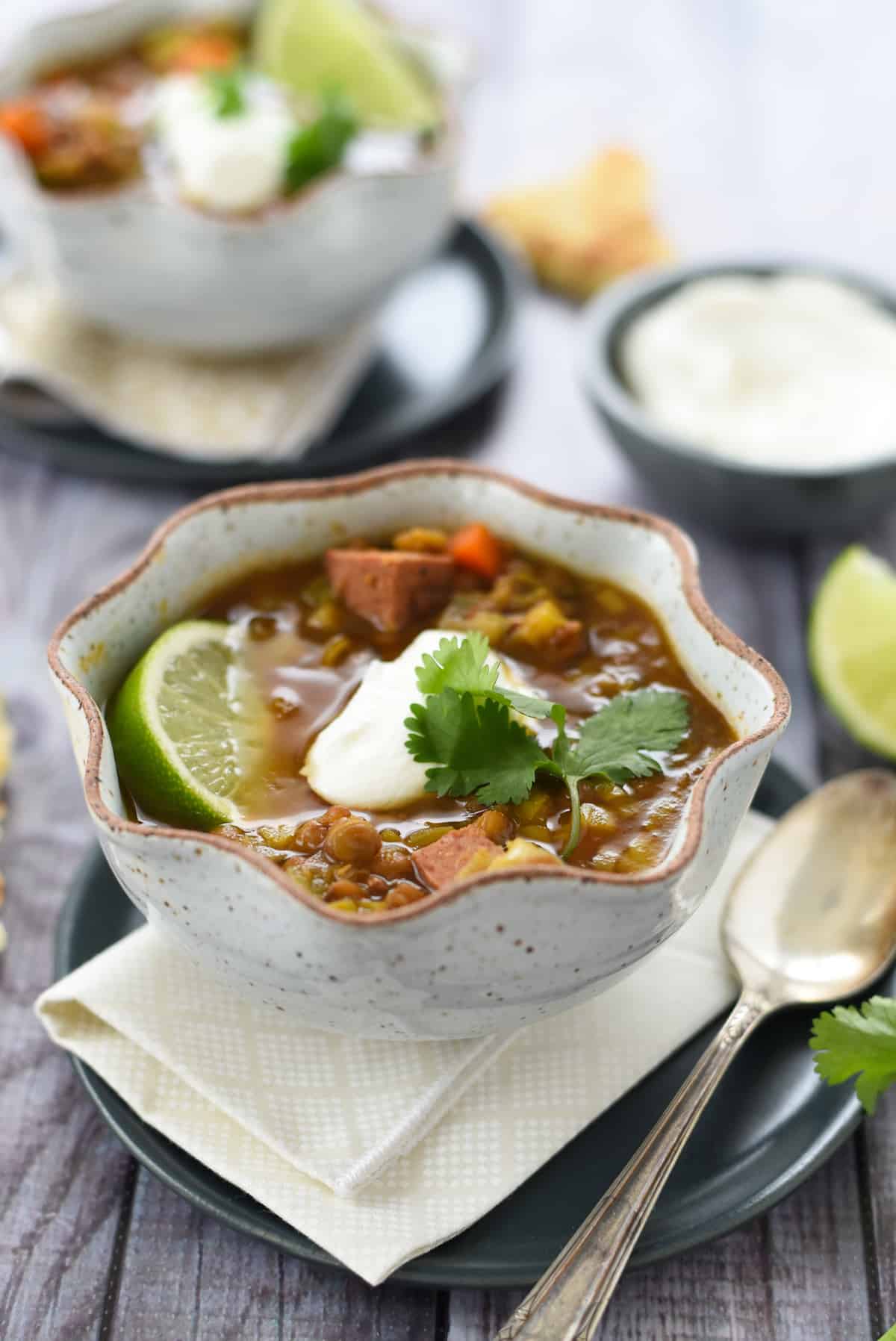 Pressure cooker lentil and sausage soup in a rustic bowl with spoon next to it.