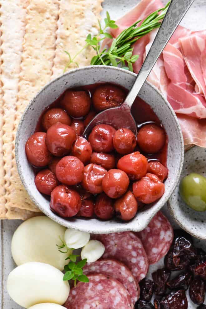 Handmade ceramic bowl filled with pickled tart cherries.