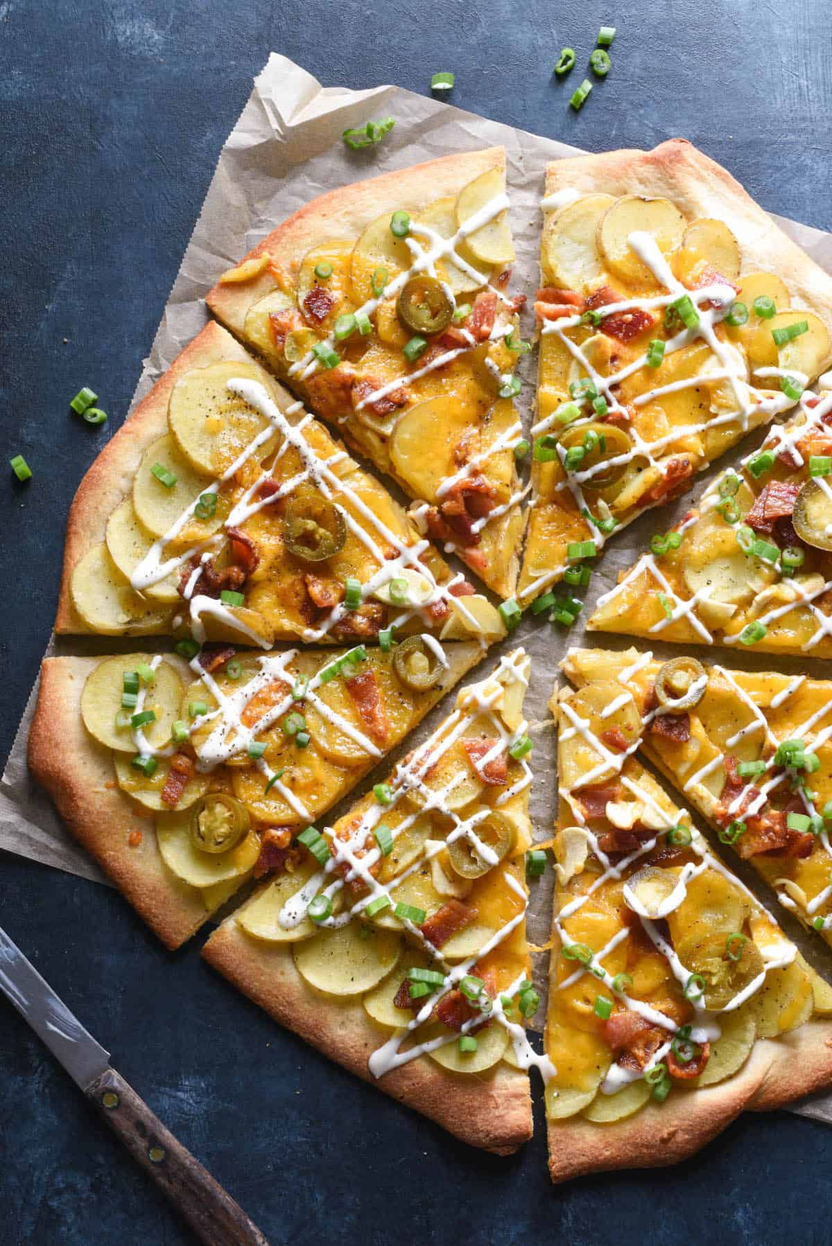 Pizza topped with potatoes, cheese, bacon, jalepeno peppers and green onions.