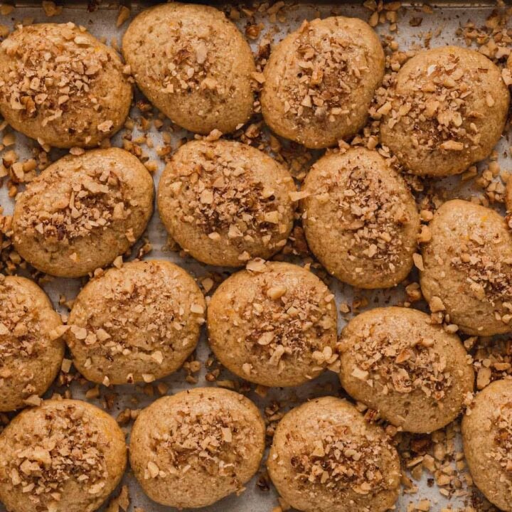 A rimmed baking pan lined with parchment paper, topped with melomakarona.