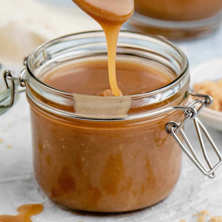 A spoon drizzling microwave caramel sauce into a small glass jar.