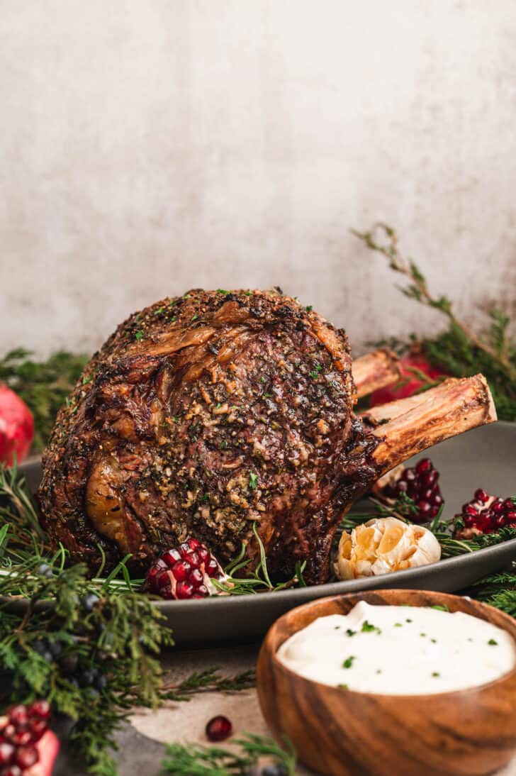 A standing rib roast covered in prime rib rub in a festive holiday dinner table scene.