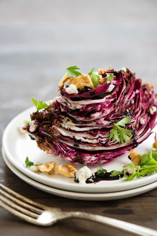 Wedge of radicchio topped with balsamic glaze, nuts, cheese and herbs.