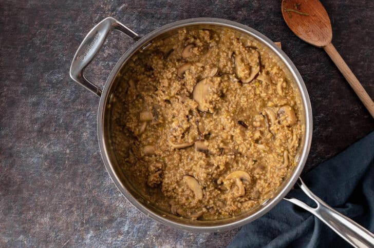 A skillet of savory oatmeal with mushrooms.