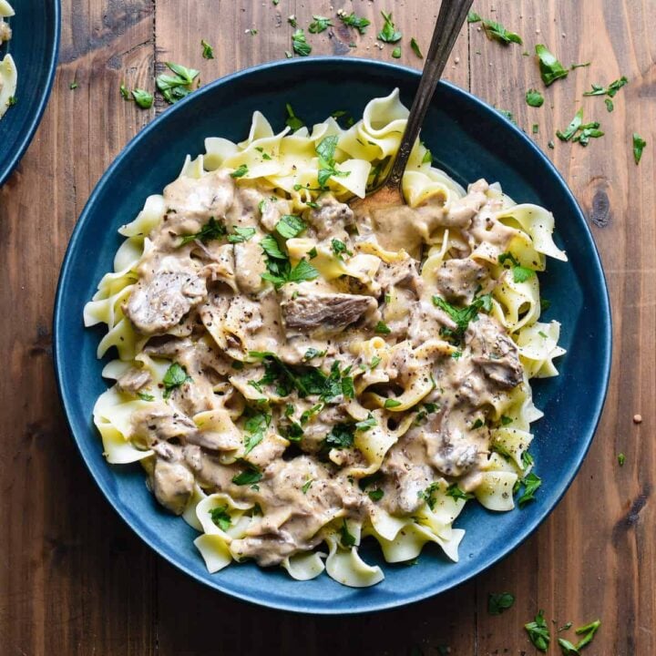 Blue ceramic bowl filled with slow cooker beef stroganoff served over egg noodles.