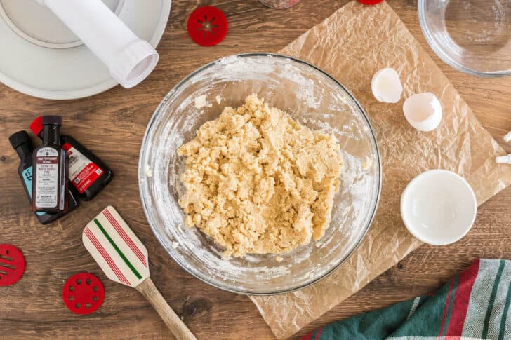 A glass bowl with a light brown cookie dough mixture in it.