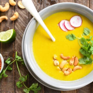 Overhead photo of curried potato soup in gray bowl, topped with cashews, cilantro and radishes.