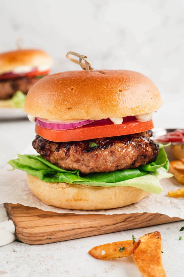 A turkey burger on a brioche bun with lettuce, tomato, onion and mayonnaise.